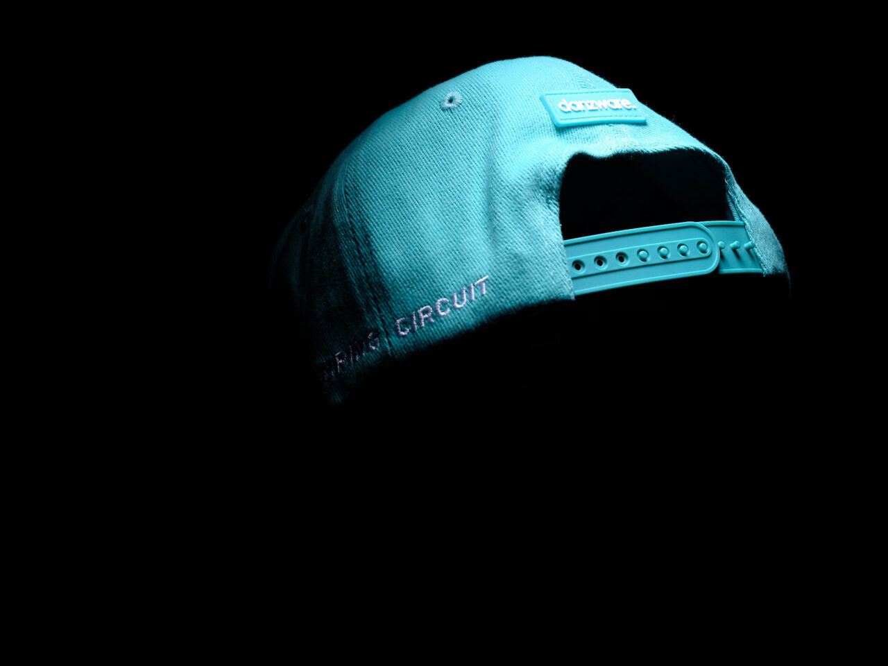 Türkisfarbenes Cap mit verstellbarem Verschluss und angeschnittener Aufschrift von 'SACHSENRING CIRCUIT' auf der Rückseite.