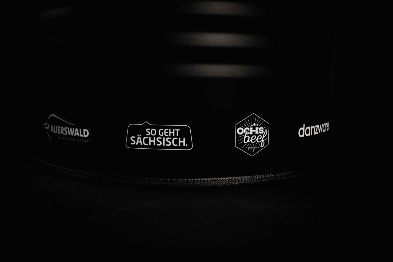 Schwarz-mattes Superenduro Stehfass von der Fasswerkstatt mit der Aufschrift "So geht sächsisch" und weiteren Labels