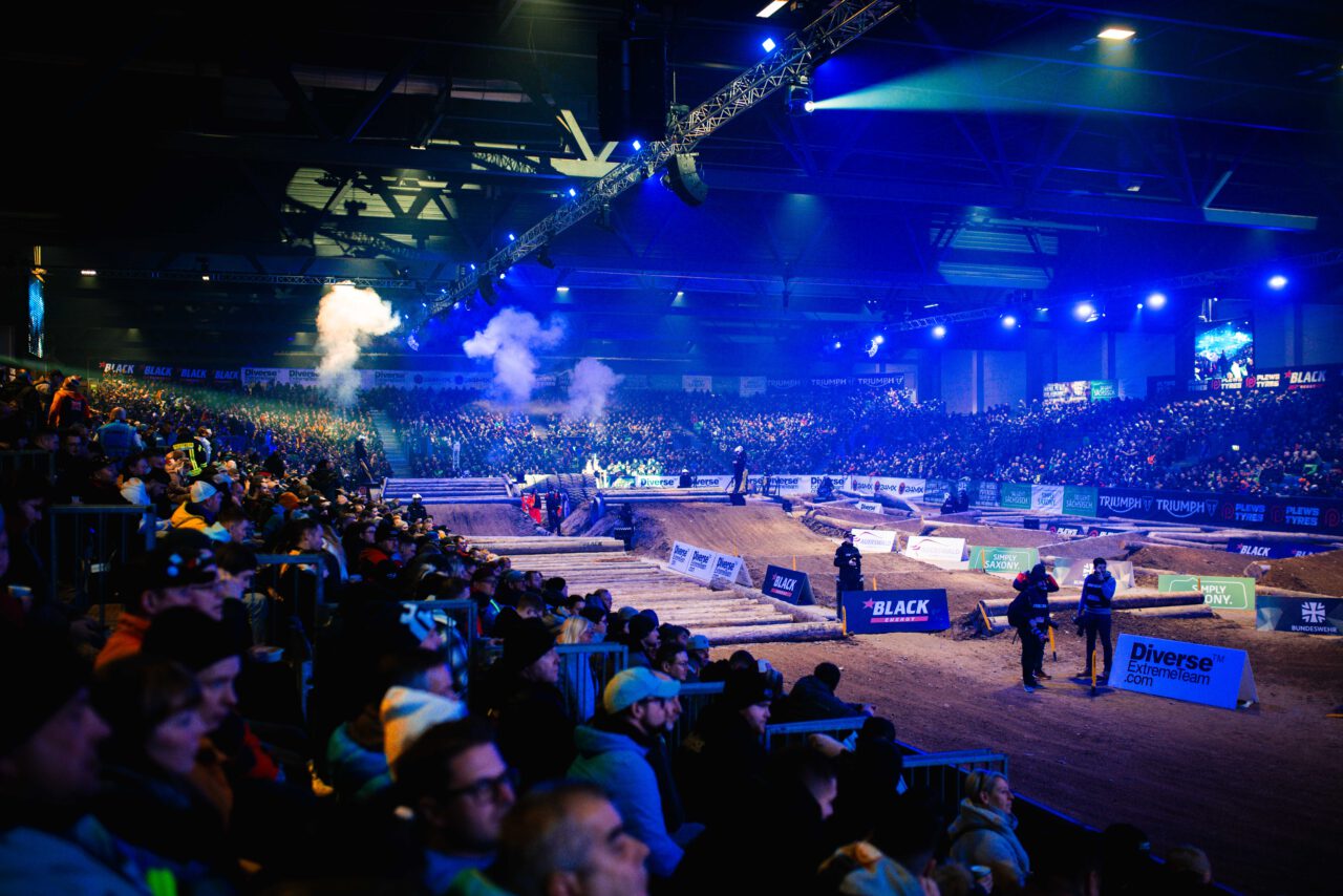 Zuschauer verfolgen gespannt ein Motocross-Rennen in einer großen Arena.
