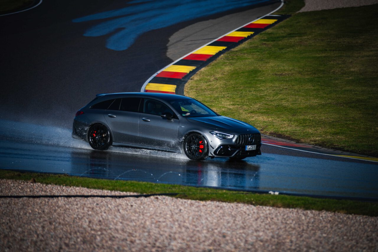 Dunkelgrauer, metallic Mercedes fährt Kurve auf präparierter nasser Strecke.