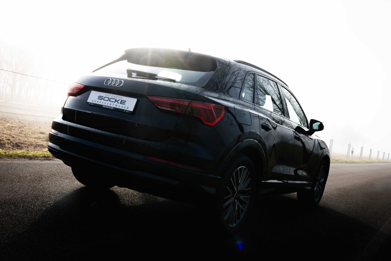 Schwarzer Audi Q3 von hinten im Nebel mit Sonnenlicht von Autohaus Socke