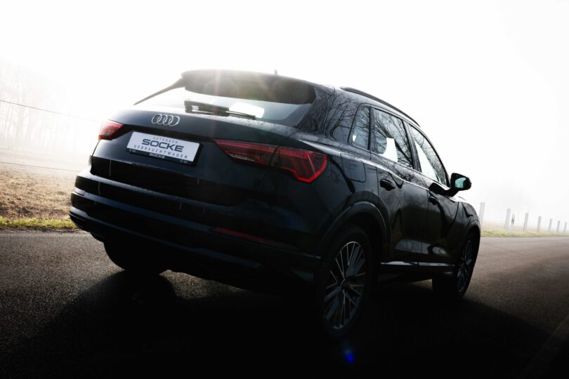 Schwarzer Audi Q3 von hinten im Nebel mit Sonnenlicht von Autohaus Socke