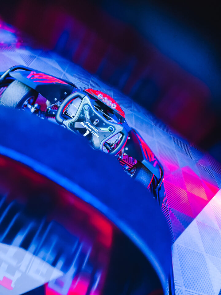 Nahaufnahme eines schwarzen und roten Virtual-Reality-Headsets auf einem karierten Untergrund mit blau-roter Beleuchtung.