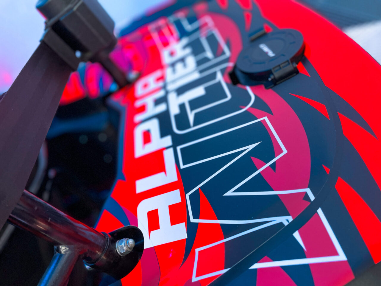 Nahaufnahme eines roten Objekts mit weißer Aufschrift 'ALPHA' TIER und weißer Schrift 'WOLF' in stilisierter Schrift.