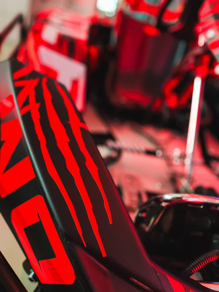 Nahaufnahme eines schwarzen Objekts mit roten Linien und roten Buchstaben, unscharfer Hintergrund mit technischen Geräten