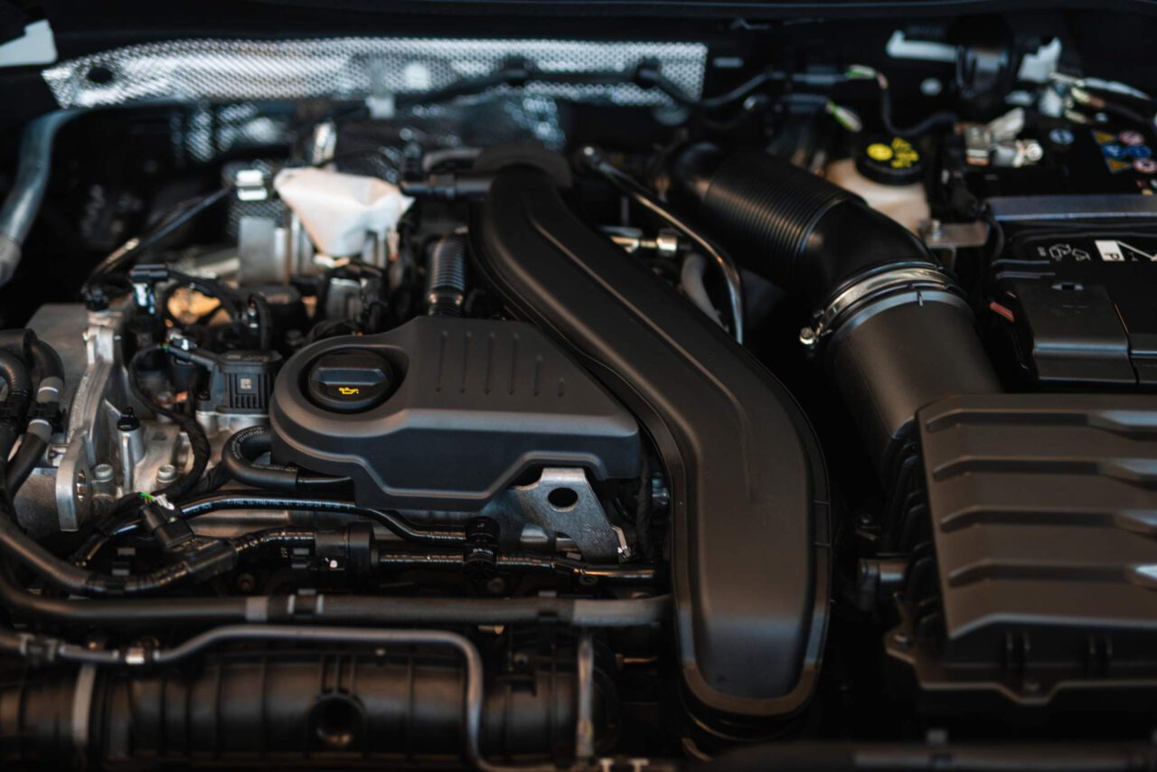 Nahaufnahme eines modernen Fahrzeugmotors mit sichtbarem Ölverschlussdeckel und Luftansaugrohr