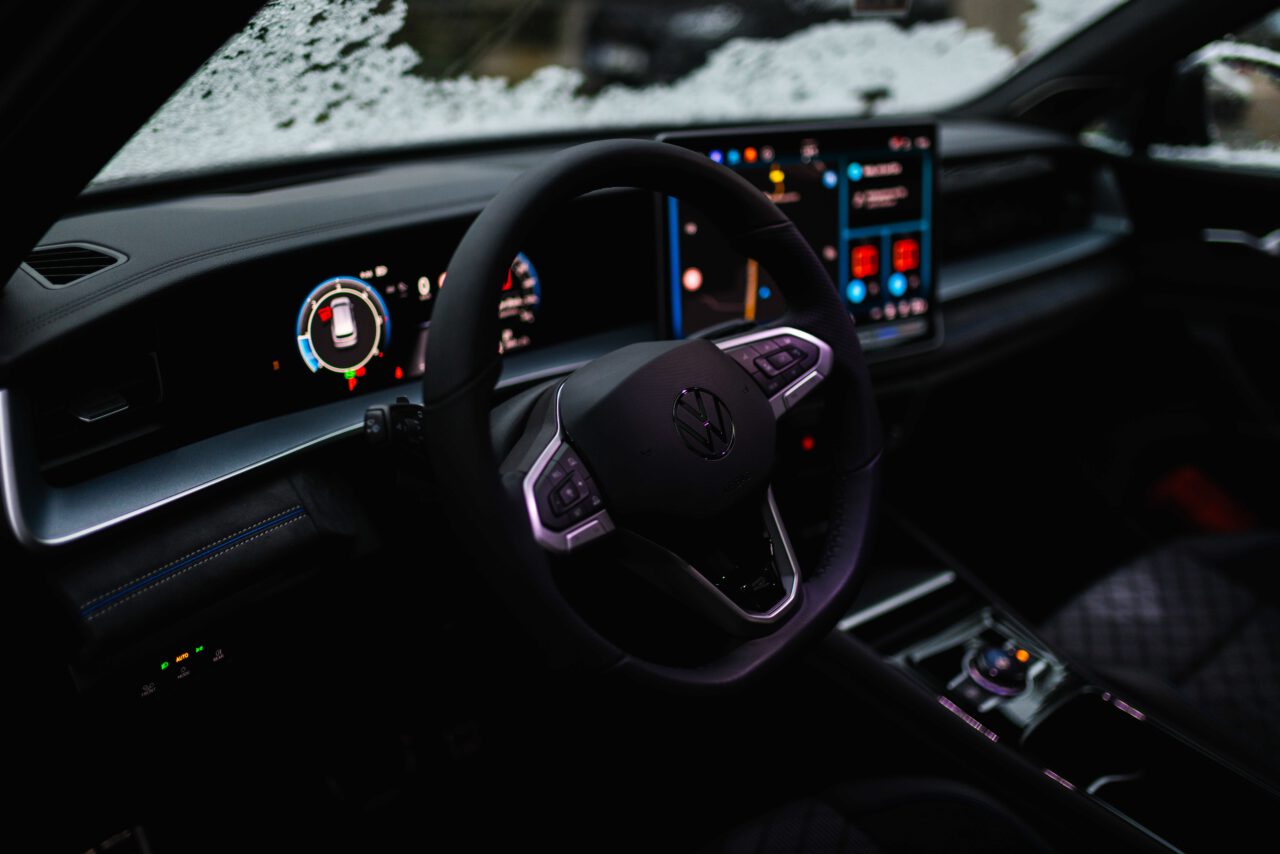 Innenraum eines Volkswagen mit beleuchtetem digitalen Armaturenbrett und Multifunktionslenkrad bei Dämmerung