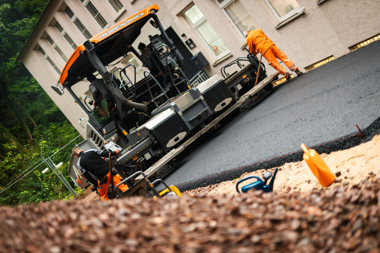 Professionelle Asphaltierung eines Gewerbehofs: Legen des Asphalts von Asphalt-Bau Chemnitz im Einsatz bei der Mindwork GmbH.