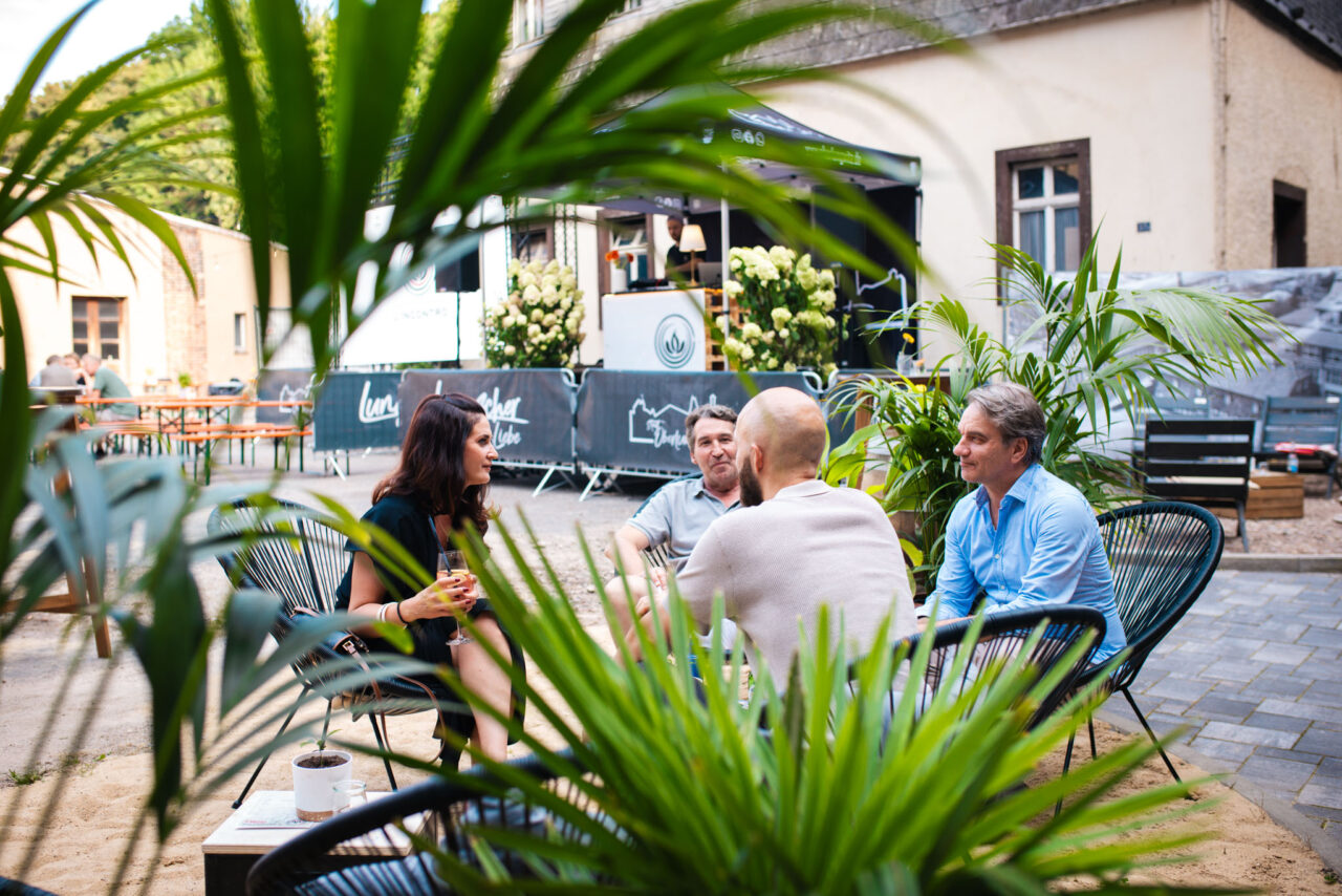 Networking-Veranstaltung im Freien: Personengruppe im Gespräch bei einem Sommerevent in einer rustikalen Event-Location.