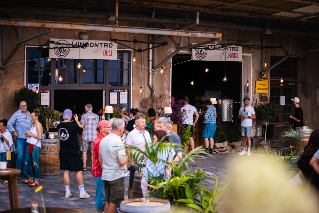 Sommerliches Get-together vor einer Industrie-Kulisse mit Bewirtung, Stehfässern und moderner Event-Ausstattung.