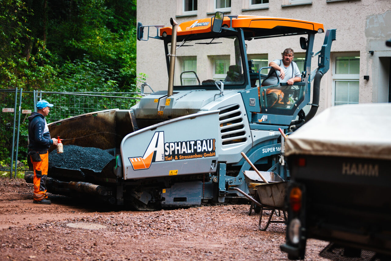 Asphaltfertiger der Firma Asphalt-Bau Chemnitz bei der Parkplatzsanierung im Industrie-Hof von Mindwork.
