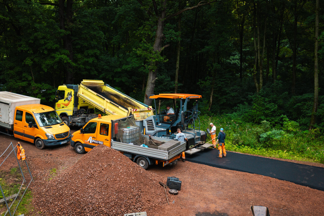 Professionelle Asphaltierung eines Gewerbehofs: Ein Asphaltfertiger und Kipper von Asphalt-Bau Chemnitz im Einsatz bei der Mindwork GmbH.